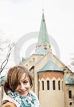 Young caucasian woman posing with parish church of saint Stephen