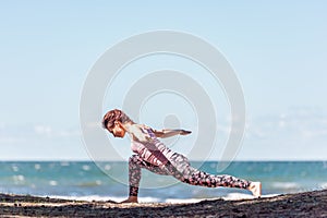 Young caucasian woman practicing yoga at seashore