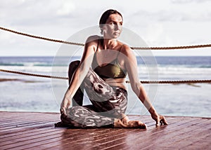 Young caucasian woman practicing yoga, sitting in Ardha Matsyendrasana. Half spinal twist pose. Bali, Indonesia