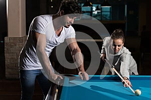 Young Caucasian Woman Receiving Advice from a man On Shooting Pool Ball While Playing Billiards