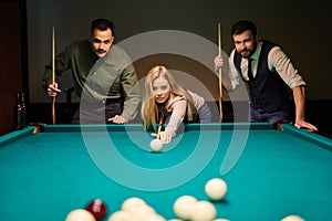 young caucasian woman receiving advice on shooting pool ball while playing billiards with friends