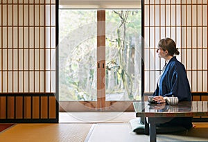 A young caucasian woman is relaxing at a traditional Japanese drinking a tea