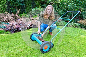 Young caucasian woman reparing lawn mower in garden