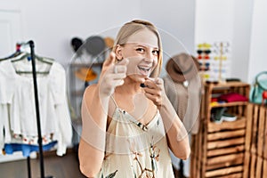 Young caucasian woman at retail shop pointing fingers to camera with happy and funny face