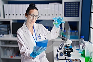 Young caucasian woman scientist using touchpad holding test tube at laboratory