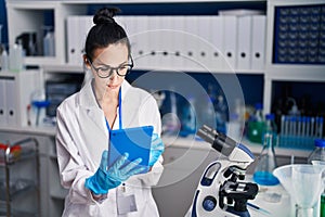 Young caucasian woman scientist using touchpad with relaxed expression at laboratory