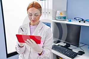 Young caucasian woman scientist using touchpad with serious expression at laboratory