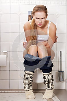 Young caucasian woman is sitting on the toilet. urinary bladder