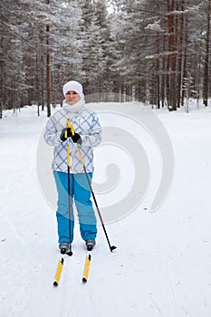 Young Caucasian woman skiing in winter snowy forest with pleasure