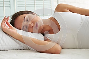 Young Caucasian woman sleeping in a relaxing pose in the bed