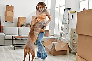 Young caucasian woman smiling confident listening to music and dancing with dog at home