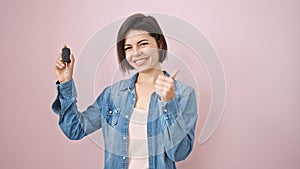 Young caucasian woman smiling doing thumbs up holding key of new car over isolated pink background