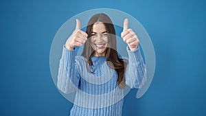 Young caucasian woman smiling with thumbs up over isolated blue background
