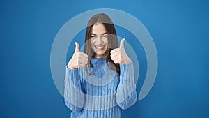 Young caucasian woman smiling with thumbs up over isolated blue background