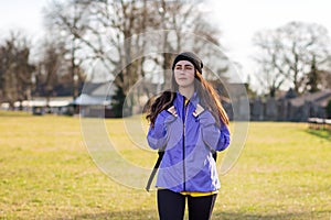 A young Caucasian woman in sportswear with a backpack behind her is walking on the lawn. Close up. The concept of sport and active