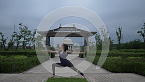 Young caucasian woman in sportswear relaxing by practicing yoga barefoot in the city park. Sunrise background. Slow