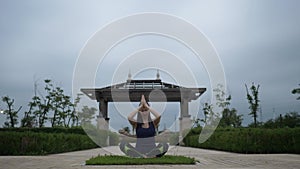 Young caucasian woman in sportswear relaxing by practicing yoga barefoot in the city park. Sunrise background. Slow