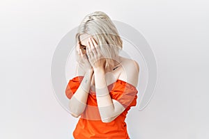 Young caucasian woman standing over isolated background with sad expression covering face with hands while crying