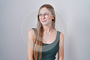 Young caucasian woman standing over white background smiling looking to the side and staring away thinking