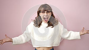 Young caucasian woman standing with surprise expression and raised arms over isolated pink background