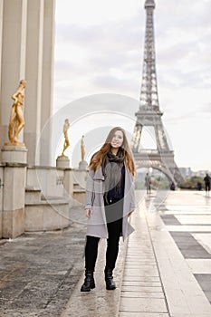 Young caucasian woman standing on Trocadero square near gilded statues and Eiffel Tower.