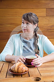 Young Caucasian woman with straight hair drinking tea in a coffee shop