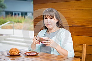 Young Caucasian woman with straight hair drinking tea in a coffee shop