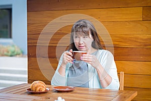 Young Caucasian woman with straight hair drinking tea in a coffee shop