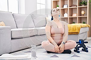 Young caucasian woman stretching head sitting on floor at home