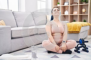 Young caucasian woman stretching head sitting on floor at home