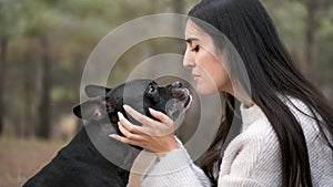 Young caucasian woman stroking and being kissed by her mixed breed dog.