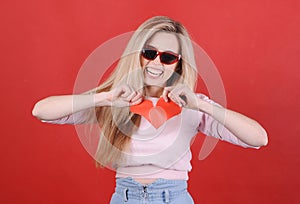 Young caucasian woman in sunglasses with broken red heart in hands.