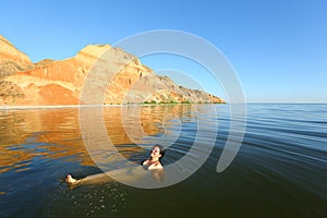 Young caucasian woman swimming in the Black sea at picturesque sunset landscape of Stanislav mountains