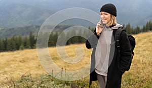Young caucasian woman talking using a smartphone in the mountains. The concept of freedom, happiness, travel and