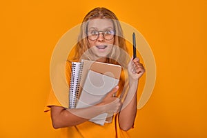 Young Caucasian woman teacher holding workbooks and pointing up with pen