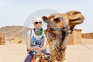 Young caucasian woman tourist riding on camel