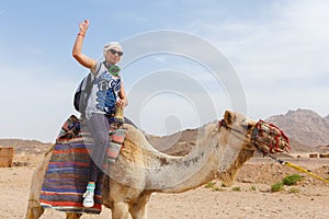 Young caucasian woman tourist riding on camel