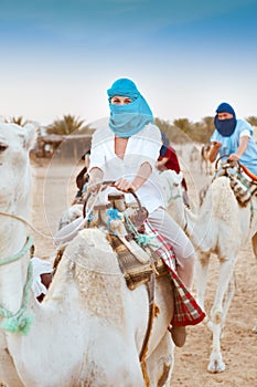 Young caucasian woman tourist riding on camel in Sahara desert