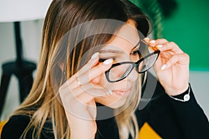 Young caucasian woman trying on glasses in opticians store, close up