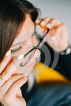 Young caucasian woman trying on glasses in opticians store, close up