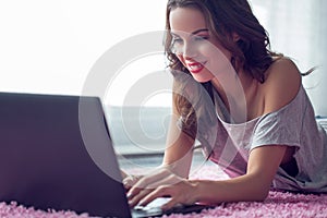 Young caucasian woman typing on laptop on carpet