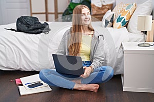 Young caucasian woman using laptop sitting on floor at bedroom