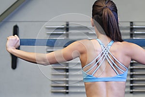 Young Caucasian woman using a resistance rubber band to tone her back