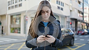 Young caucasian woman using smartphone looking upset at street