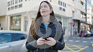 Young caucasian woman using smartphone looking upset at street