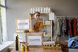 Young caucasian woman volunteer uniform holding donations box at charity center