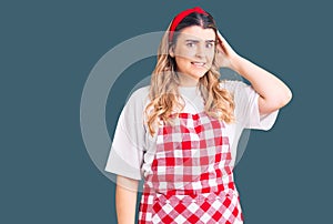Young caucasian woman wearing apron confuse and wonder about question