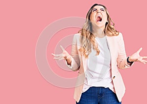 Young caucasian woman wearing business clothes crazy and mad shouting and yelling with aggressive expression and arms raised