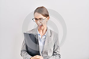 Young caucasian woman wearing business clothes and glasses angry and mad screaming frustrated and furious, shouting with anger