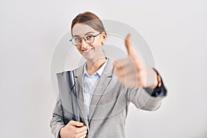 Young caucasian woman wearing business clothes and glasses approving doing positive gesture with hand, thumbs up smiling and happy